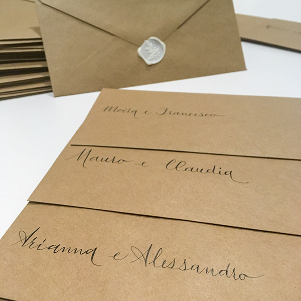 coordinato grafico matrimonio: buste marroni con nomi scritti a mano con tecnica calligrafica e timbro in cera bianco